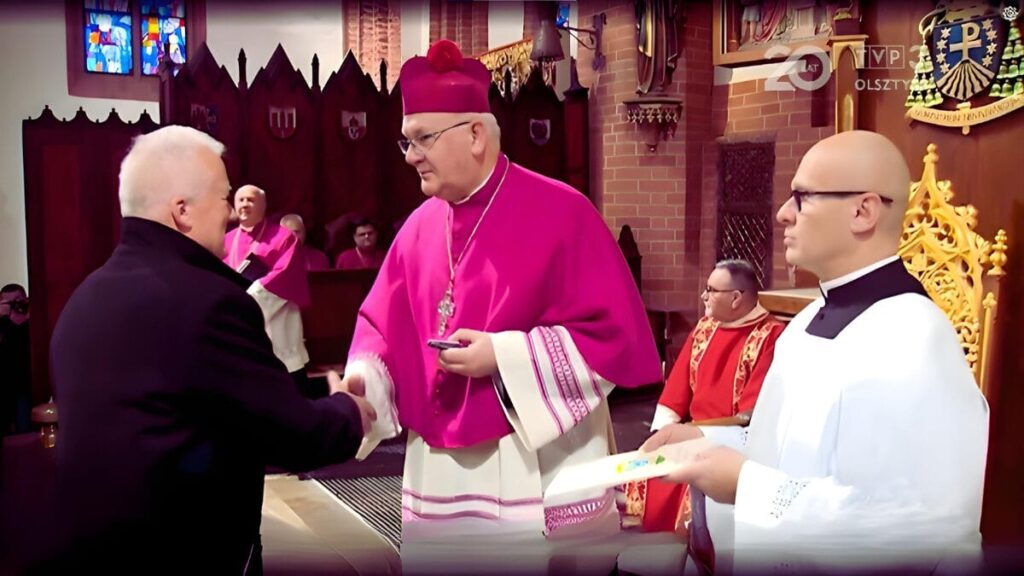 Moment Uhonorowania. Arcybiskup Józef Górzyński Wręcza Order Prodesse Auso Andrzej Kowalski – W Uznaniu Wieloletniej Służby Kościołowi I Pracy Na Rzecz Wspólnoty.Źródło: Screen Z Materiału Tvp3 Olsztyn.